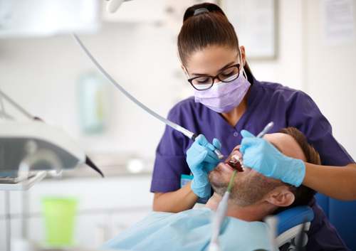 dentist drilling tooth to patient