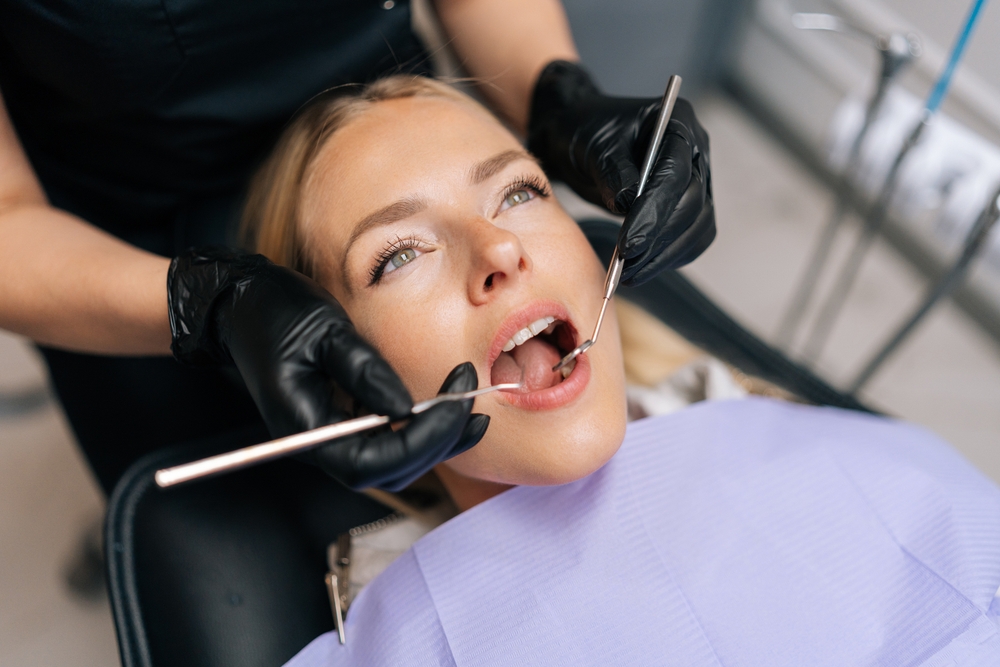 Dentist using a mirror and scaler to examine a reclined patient's teeth during a routine orthodontic checkup at Bagoff Dental Arts
