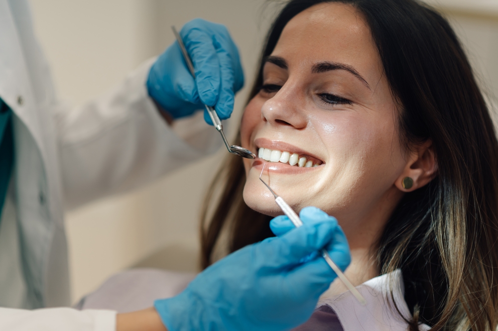 Smiling patient receiving a dental exam with a mirror and explorer at a family and cosmetic dental practice