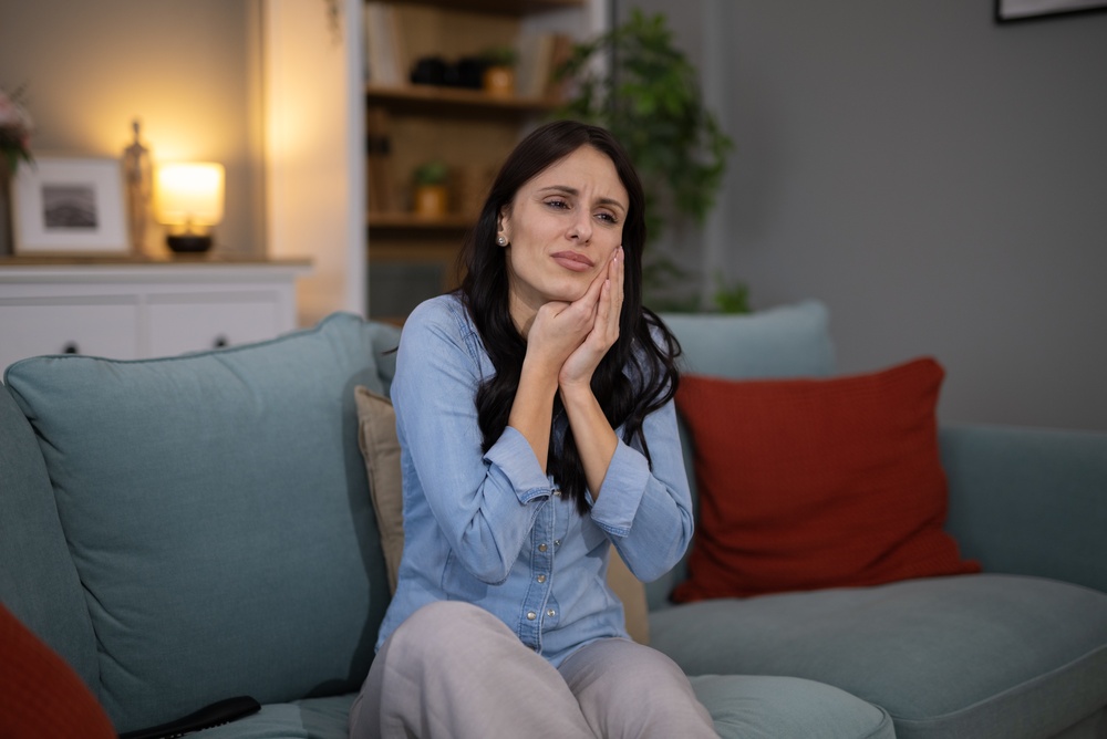 Woman cradling her aching gums with both hands, a sign it is time to call an periodontist in West Orange, NJ