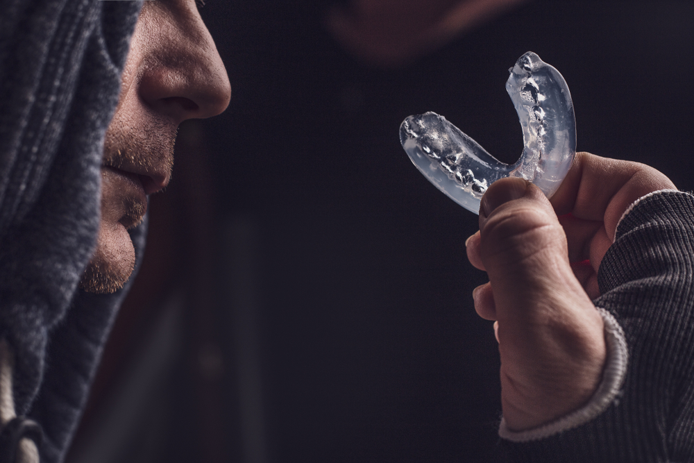 Man examining a clear custom mouthguard before wearing it for sports protection
